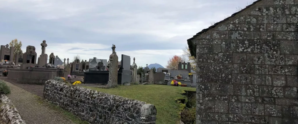 Cimetière communal traditionnel avec monuments funéraires en pierre et mur de soutènement